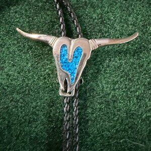 Western-style bolo tie featuring a central pendant in the shape of a steer skull